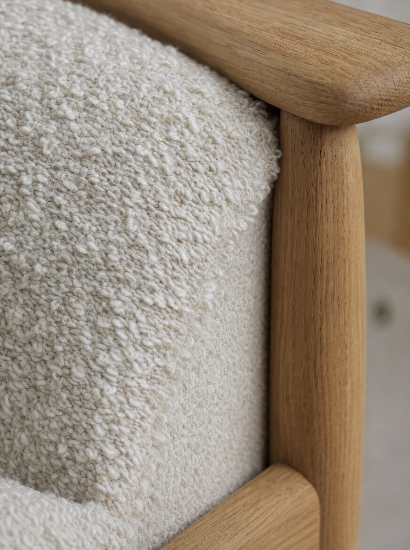 Détail du fauteuil Lubéron : la bouclette de laine rencontre l’accotoir en chêne huilé, boucles du fil et couture d’assemblage