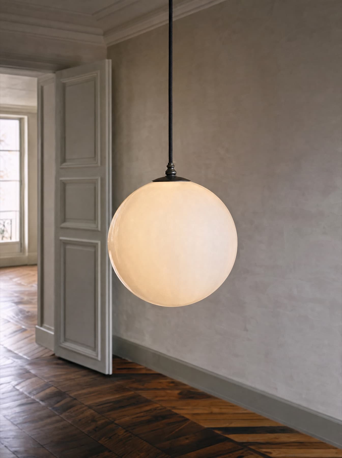 Suspension Trieste, globe de verre opalin soufflé bouche suspendu à un câble textile noir, lumière diffuse et sans point chaud