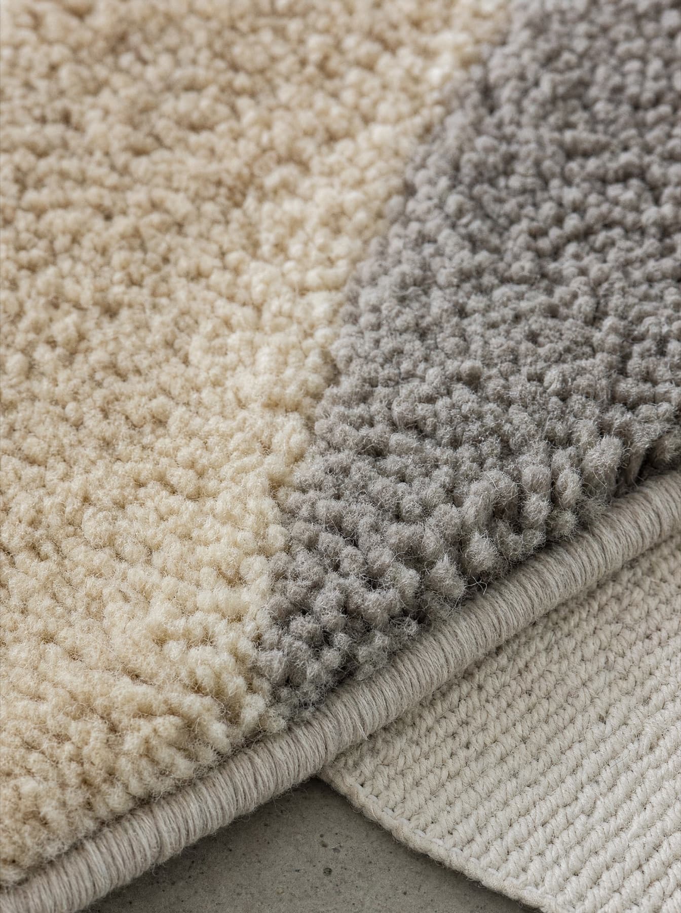 Détail du tapis Morvan : la limite entre deux blocs de velours coupé, les touffes de laine dressées et l’envers coton en bordure